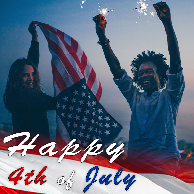 Two friends celebrate the 4th of July, waving an American flag as sparks fly at dusk.
